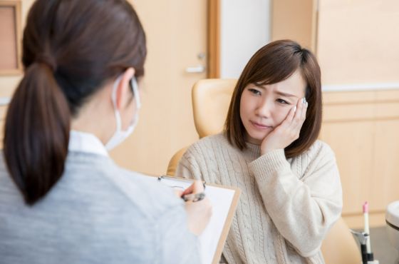 頬をおさえる女性